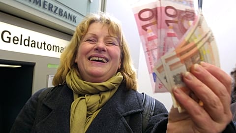 Hildegard Stein laughs as she waves euro bills she got from an ATM in a bank in Frankfurt, Germany, shortly after midnight Tuyesday Jan. 1, 2002. 