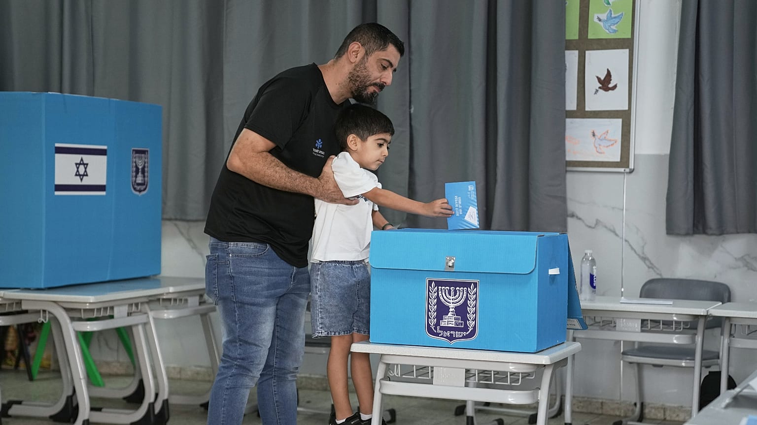 Ισραηλινός ψηφοφόρος ρίχνει την ψήφο του στην κάλπη με την βοήθεια του μικρού γιου του