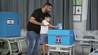 Ισραηλινός ψηφοφόρος ρίχνει την ψήφο του στην κάλπη με την βοήθεια του μικρού γιου του
