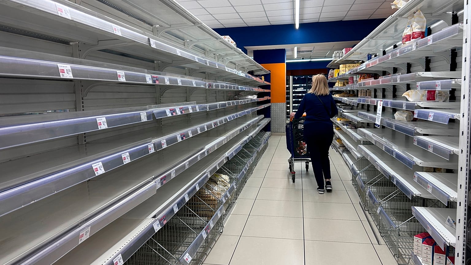 A woman walks past empty supermarkets shelves after a trucker strike brought food transport to a standstill in southern Italy, October 2026