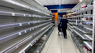 A woman walks past empty supermarkets shelves after a trucker strike brought food transport to a standstill in southern Italy, October 2026