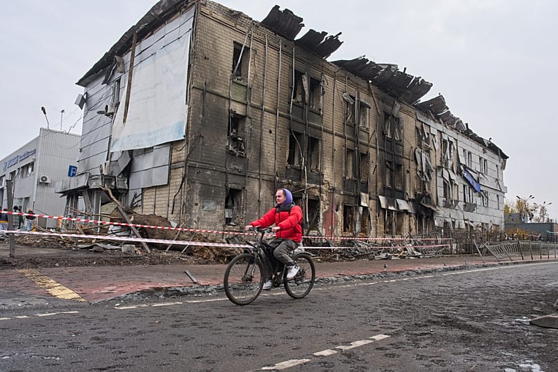 Mężczyzna jedzie na rowerze obok budynku zniszczonego podczas nocnego rosyjskiego nalotu w Kijowie na Ukrainie, 27 października 2026 r. 