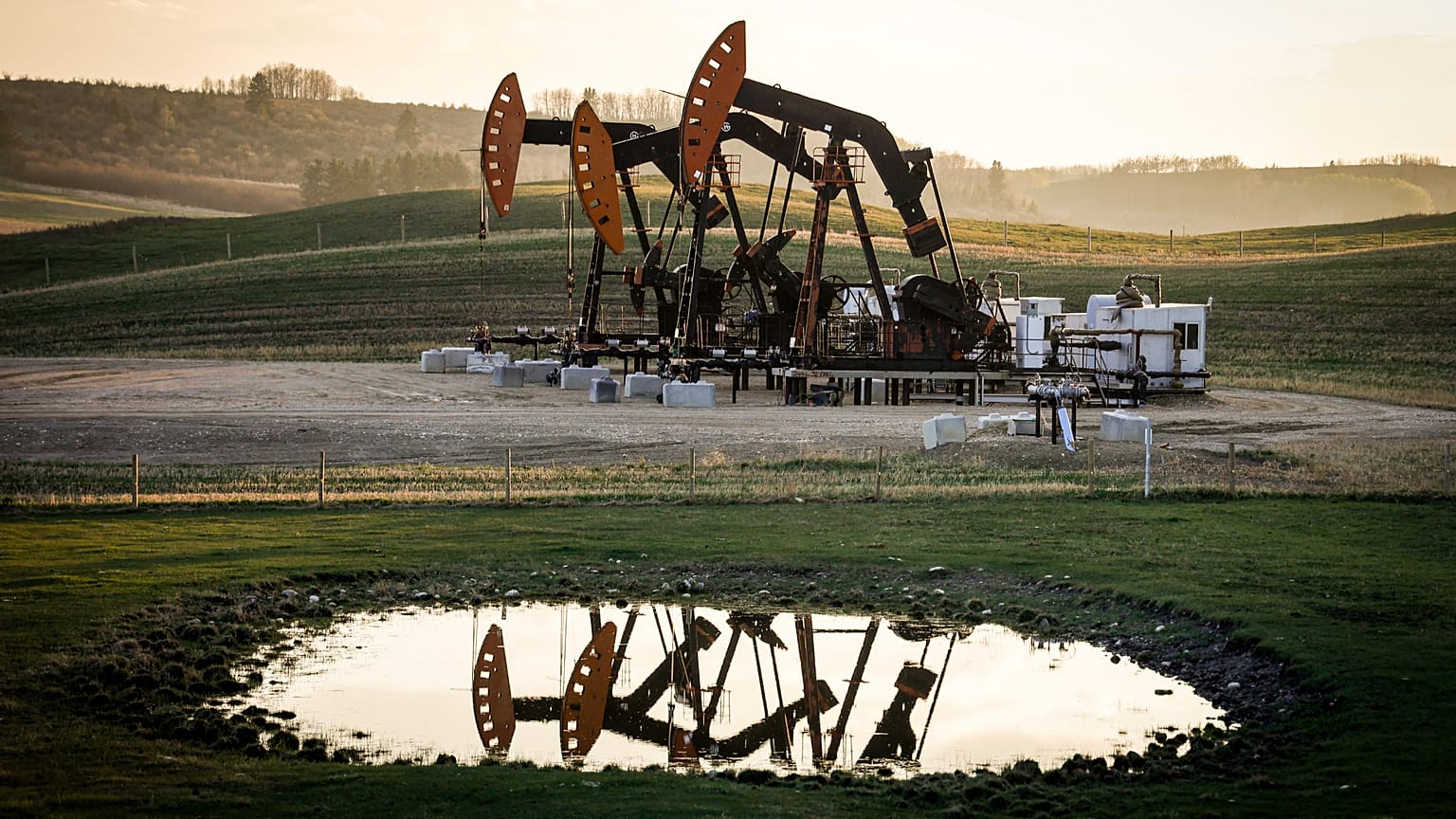 Des pompes à balancier extraient pétrole et gaz des têtes de puits, tandis que la fumée des feux de forêt flotte dans l'air près de Calgary, en Alberta, le 12 mai 2024.