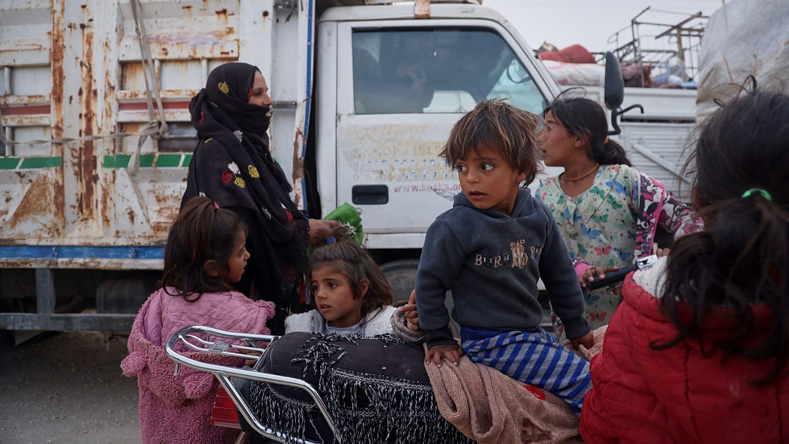 أطفال يراقبون استعداد نحو 450 عائلة لمغادرة مخيم الطلائع بالحسكة، عائدين لريف رأس العين بعد 7 سنوات من تهجيرهم جراء هجوم عسكري ترك