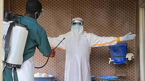 A healthcare worker in protective clothing is disinfected by a colleague inside a treatment center for Ebola patients in Beni, North Kivu province, eastern Congo.