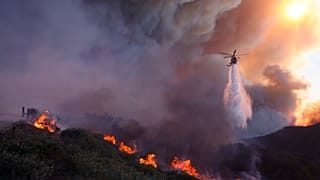 آرشیو - یک بالگرد روی آتش‌سوزی در حال گسترش پالیسیدز در محله پاسفیک پالیسیدز لس آنجلس، ۷ ژانویه ۲۰۲۵ آب می‌ریزد.