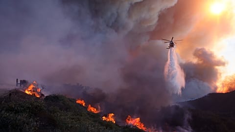 FILE - Water is dropped by helicopter on the advancing Palisades Fire in the Pacific Palisades neighborhood of Los Angeles, Jan. 7, 2025.