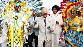 Le roi Charles III secoue des cloches de vache traditionnelles en défilant avec des danseurs de Junkanoo lors d'un festival culturel à Rawson Square, à Nassau, aux Bahamas.