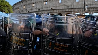 Italian anti-riot police watch antiwar activists demonstrating against rearmament and Italy's involvement in wars in front of the Colosseum in Rome, Saturday, Oct. 24, 2026