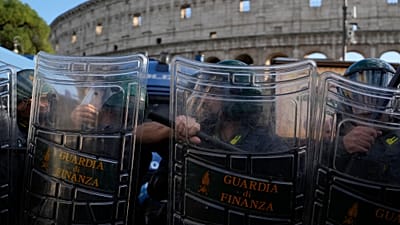 Italian anti-riot police watch antiwar activists demonstrating against rearmament and Italy's involvement in wars in front of the Colosseum in Rome, Saturday, Oct. 24, 2026