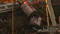 Cranes lift wrecked train carriages as rescuers search for victims following a collision between two trains in Urda, Spain.