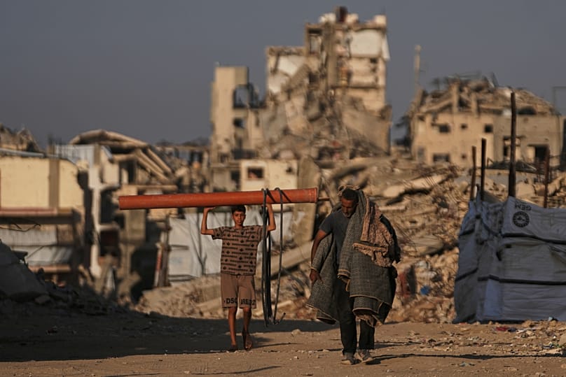 فلسطينيون يسيرون بين مبانٍ دمرتها الحرب الإسرائيلية على غزة، 28 أكتوبر 2026.