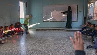 معلمة تقدّم درساً للطلاب داخل أحد فصول مدرسة "معر شمارين" الابتدائية في قرية معر شمارين، بريف إدلب في سوريا