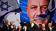Gadi Eisenkot, leader of the Yashar ("Straight") party, waves an Israeli flag onstage following the release of the first exit poll results. 28 October 2026 