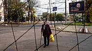 Un'anziana cammina sotto reti anti-drone tese sopra una strada durante una tregua locale legata a una missione di aiuti umanitari a Oleshky, in Ucraina, il 28 ottobre 2026.