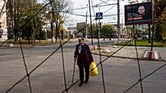 An elderly woman walks beneath anti-drone nets stretched over a street during a local ceasefire related to a humanitarian aid mission in Oleshky, Ukraine, 28 October, 2026. 