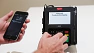 A customer makes a contactless payment using a smartphone at a point-of-sale terminal