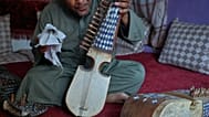 یک نوازنده افغان که پس از تعطیلی مغازه خانوادگی فروش ساز در پی تسلط طالبان، به کارگری روی آورده است، در کابل رباب، ساز زهی سنتی افغانستان، در دست دارد؛ ۱۱ اکتبر ۲۰۲۶