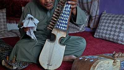 یک نوازنده افغان که پس از تعطیلی مغازه خانوادگی فروش ساز در پی تسلط طالبان، به کارگری روی آورده است، در کابل رباب، ساز زهی سنتی افغانستان، در دست دارد؛ ۱۱ اکتبر ۲۰۲۶