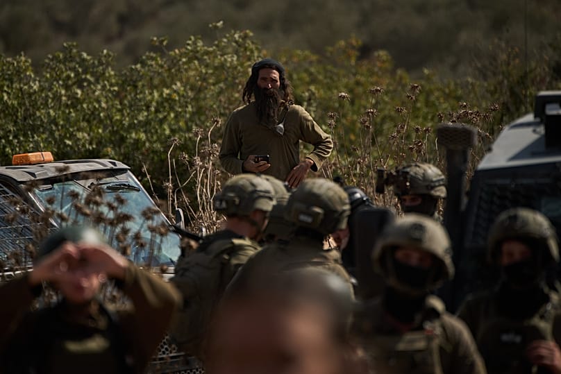 Colono israelita na Cisjordânia observa bloqueio de estrada montado pelo exército para impedir acesso dos palestinianos aos olivais