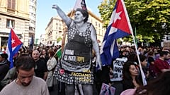 Demonstrators carry a life-size cutout of a woman raising her fist, with a message reading "We've already paid too much, now let's settle the score," 