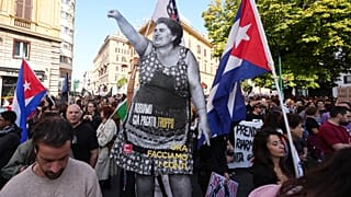 Des manifestants portent une silhouette grandeur nature d'une femme levant le poing, avec un message indiquant " *Nous avons déjà trop payé, maintenant réglons nos comptes*".