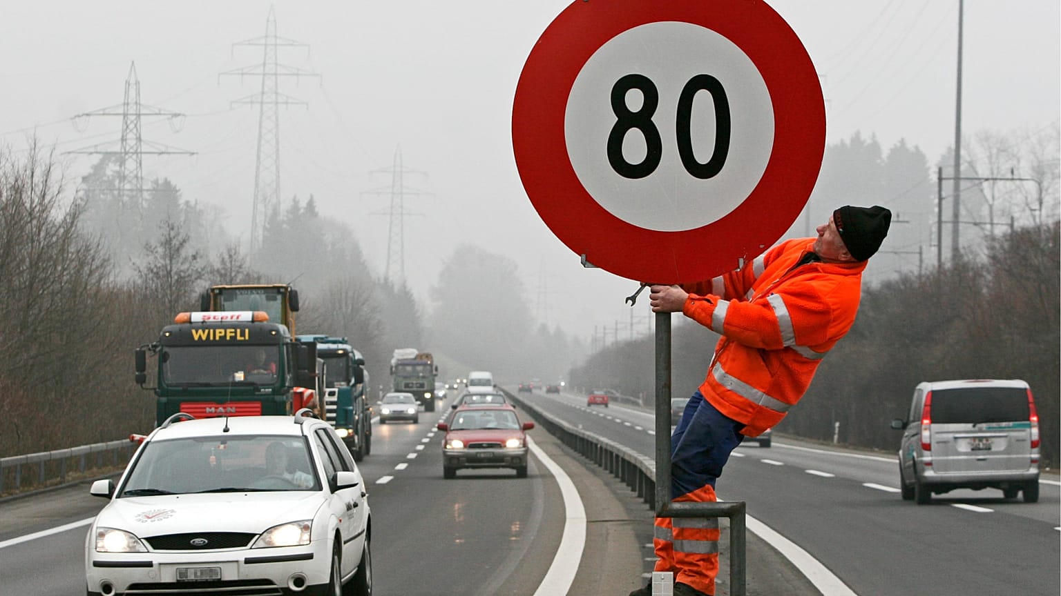 Archivfoto. Ein Arbeiter stellt am Freitag, dem 3. Februar 2006, auf der Autobahn N4 in Zug (Schweiz) ein Schild auf, das eine Geschwindigkeitsbegrenzung von 80 km/h anzeigt.