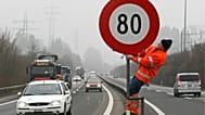 Archivfoto. Ein Arbeiter stellt am Freitag, dem 3. Februar 2006, auf der Autobahn N4 in Zug (Schweiz) ein Schild auf, das eine Geschwindigkeitsbegrenzung von 80 km/h anzeigt.