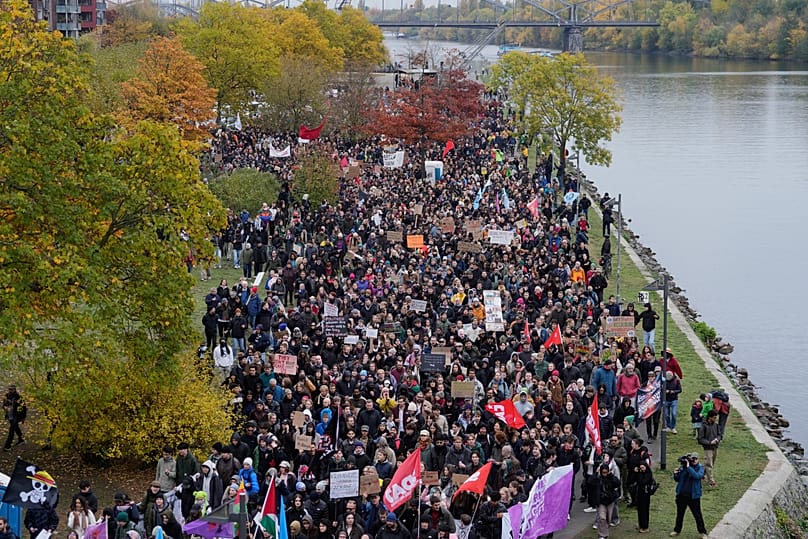 Demonstrators gather at the banks of the river. Main for a protest under the slogan "Gen Z Takes Care of It" in Frankfurt, Germany, Saturday, Oct. 31, 2026.